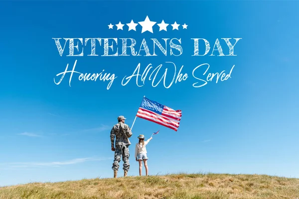 Back view of kid in straw hat and military father holding american flags with veterans day, honoring all who served illustration — Stock Photo