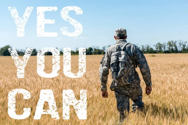 Soldier in military uniform with backpack standing in field with golden wheat with yes you can illustration — Stock Photo