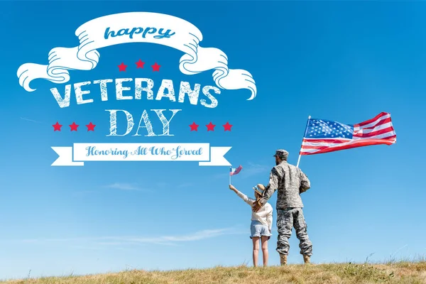 Back view of kid in straw hat and military father holding american flags with happy veterans day, honoring all who served illustration — Stock Photo