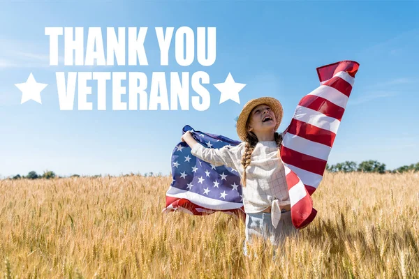Fröhliches Kind mit Strohhut und amerikanischer Flagge im goldenen Feld mit Weizen und Dankeschön-Veteranen — Stockfoto