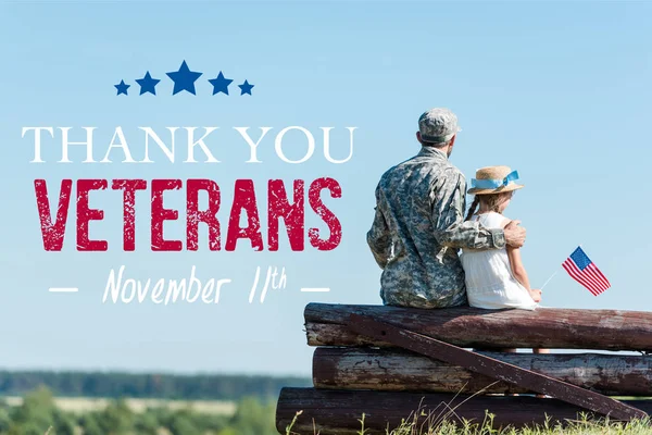 Back view of patriotic child holding american flag near veteran father while sitting in fence with thank you veterans illustration — Stock Photo