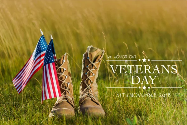 Військові черевики біля американського прапора з зірками і смугами на траві з ілюстрацією дня ветеранів — стокове фото