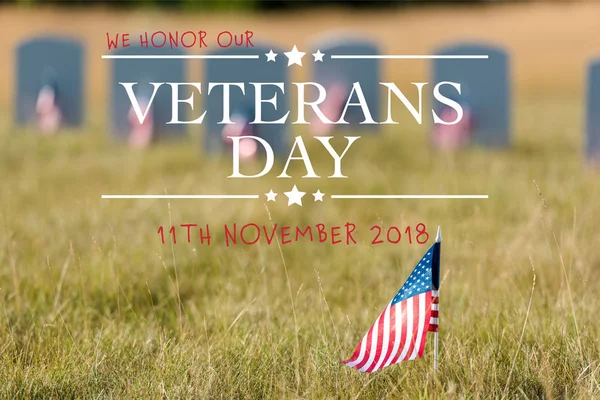 Selective focus of american flag with stars and stripes near gravestones with veterans day illustration — Stock Photo