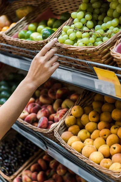 Vista recortada de la mujer haciendo gestos cerca de frutas en el supermercado - foto de stock