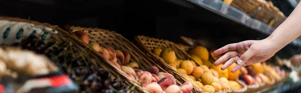 Panoramic shot of young woman near fruits in supermarket — Stock Photo