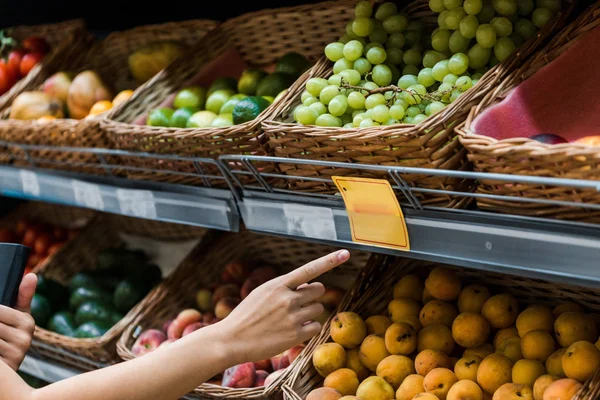 Messa a fuoco selettiva della donna che punta con il dito alla frutta nel supermercato — Foto stock