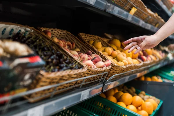 Vista cortada de mulher jovem perto de frutas no supermercado — Fotografia de Stock