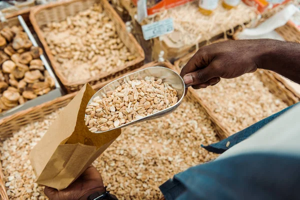Overhead-Ansicht von afrikanisch-amerikanischen Mann hält Metallschaufel mit leckeren Erdnüssen im Geschäft — Stockfoto