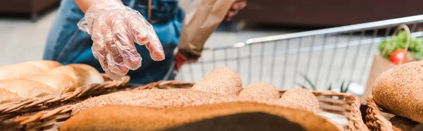 Панорамный снимок женщины в перчатках возле хлеба в супермаркете — стоковое фото