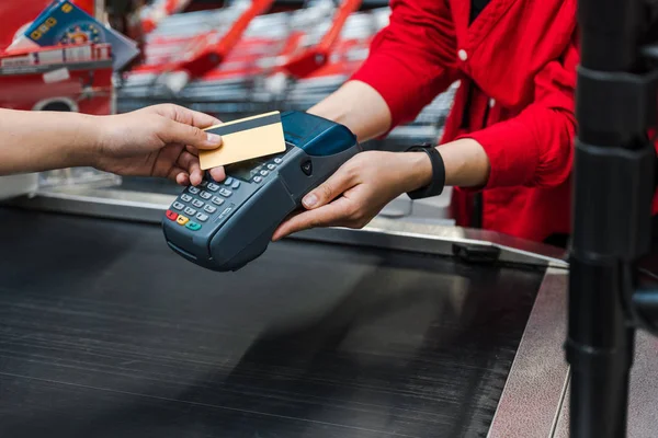 Vista recortada del cliente que paga con tarjeta de crédito cerca del cajero en el supermercado - foto de stock