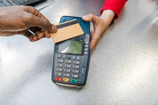 Vue du dessus de l'homme afro-américain payant par carte de crédit près de la caisse dans un supermarché — Photo de stock