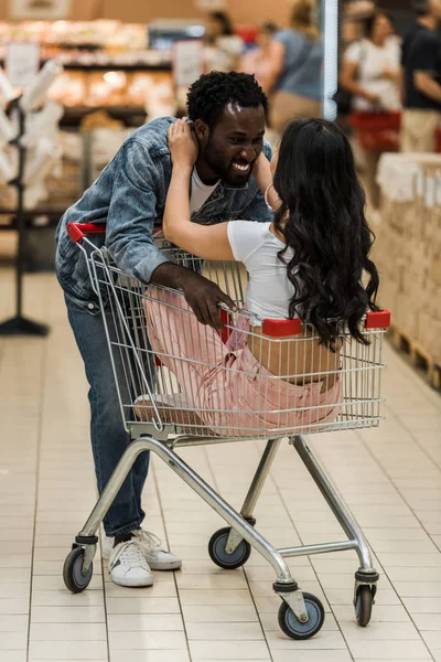 Vista posterior de chica tocando la cara de hombre afroamericano en la tienda - foto de stock