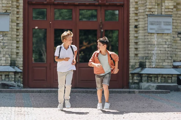 Zwei fröhliche Schüler laufen auf dem Schulhof umher, während sie einander anschauen — Stockfoto