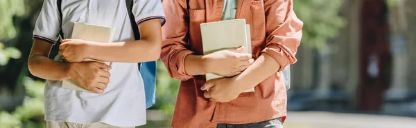 Vista ritagliata di due scolari che tengono libri, colpo panoramico — Foto stock