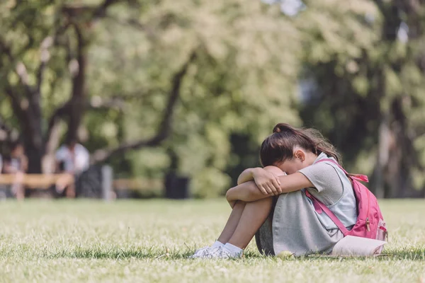 Stufa studentessa con zaino seduta sul prato verde nel parco vicino al libro — Foto stock