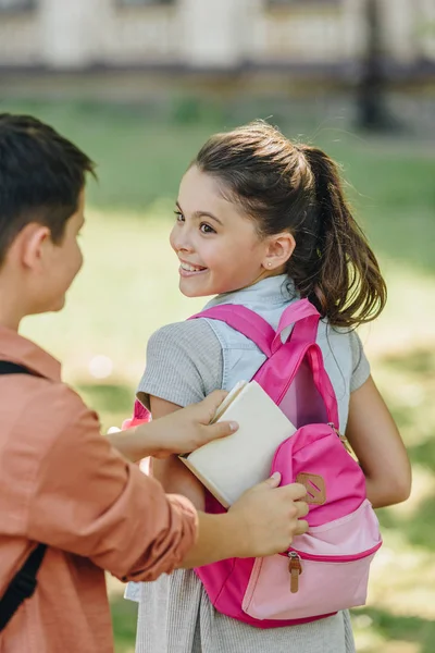 Vista parcial del libro de embalaje del colegial en la mochila de colegiala alegre - foto de stock