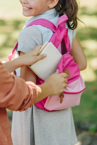 Частковий вид на шкільну книгу в рюкзаку усміхненої школярки — стокове фото