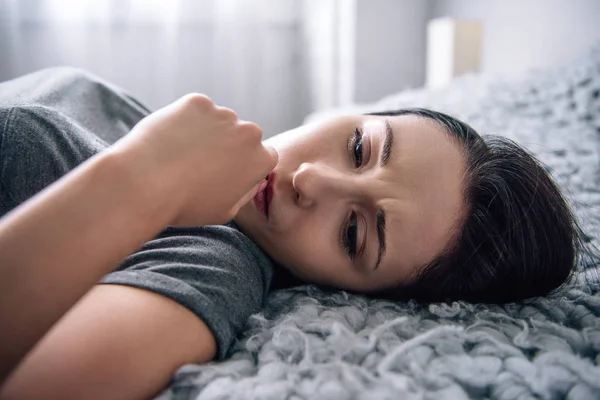 Selective focus of beautiful depressed woman lying on bed at home — Stock Photo
