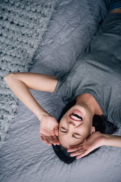 Vista aérea de la mujer deprimida acostada en la cama y llorando en casa - foto de stock