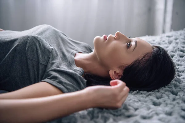 Красивая депрессивная женщина лежит на кровати дома — стоковое фото