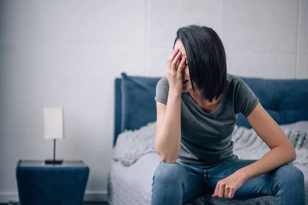 Mujer deprimida sentada en la cama en casa y llorando - foto de stock