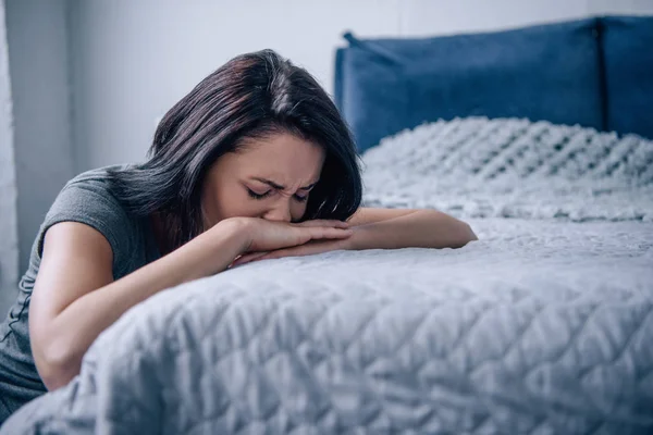 Hermosa mujer deprimida llorando y acostada en la cama en casa - foto de stock