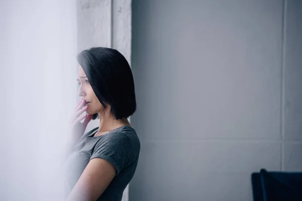 Belle femme déprimée regardant par la fenêtre à la maison avec espace de copie — Photo de stock