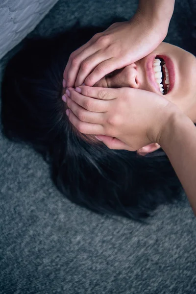 Depressed brunette woman covering face with hands and crying at home — Stock Photo