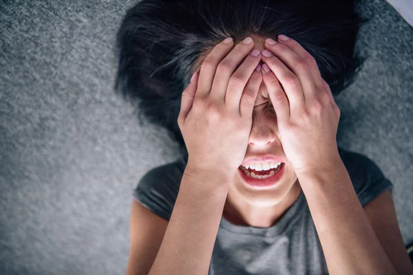 Deprimida morena solitaria mujer cubriendo la cara con las manos en casa - foto de stock