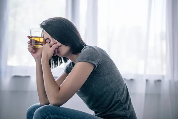Bouleversé femme solitaire avec verre de whisky à la maison — Photo de stock