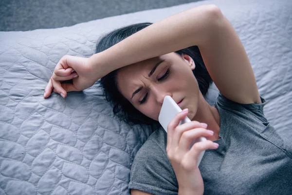 Solitário chateado mulher na cama com smartphone no quarto — Fotografia de Stock