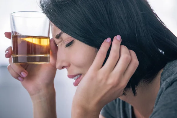 Hermosa mujer molesta con vaso de whisky en casa - foto de stock