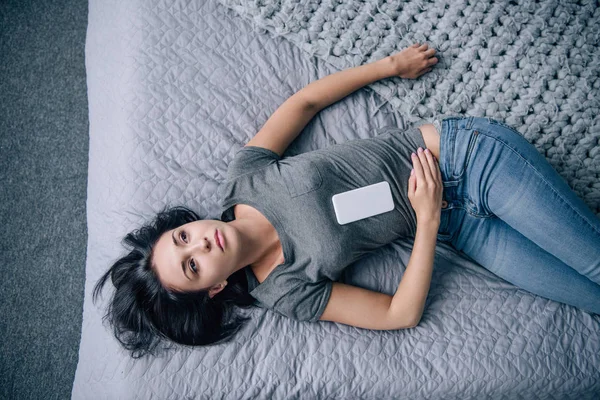 Blick von oben auf einsame Frau mit Smartphone im Schlafzimmer — Stockfoto