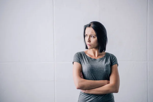 Depressed brunette woman with crossed arms at home — Stock Photo