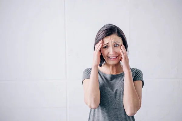 Sad brunette woman with hands on head crying at home — Stock Photo