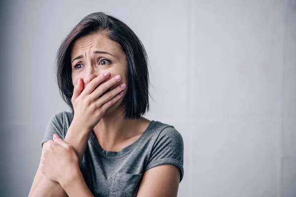 Mujer morena deprimida cubriendo la boca y llorando en casa - foto de stock