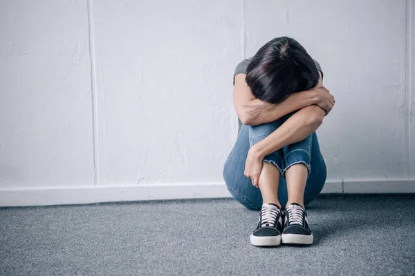 Depressive einsame brünette Frau sitzt zu Hause mit Kopierraum auf dem Boden — Stockfoto