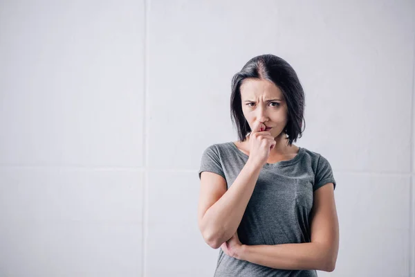 Triste pensativa mujer tocando la barbilla y mirando a la cámara en casa - foto de stock