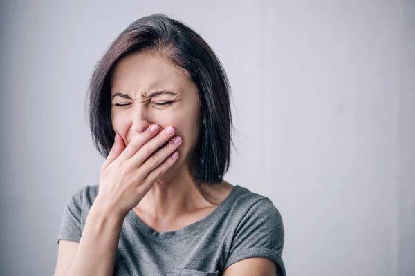 Mujer morena deprimida llorando y cubriendo la boca en casa - foto de stock