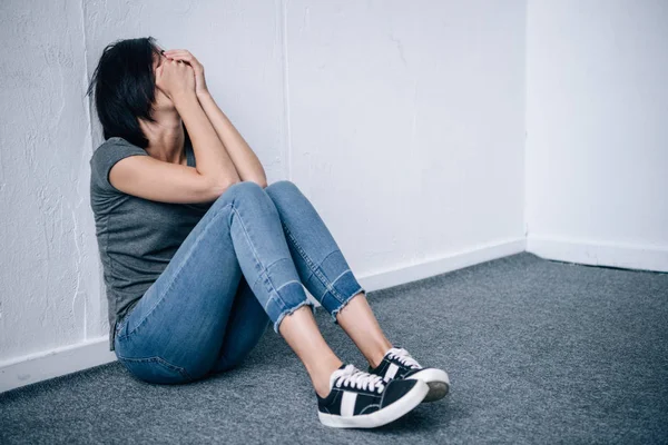 Depressive brünette Frau sitzt und bedeckt Mund zu Hause — Stockfoto