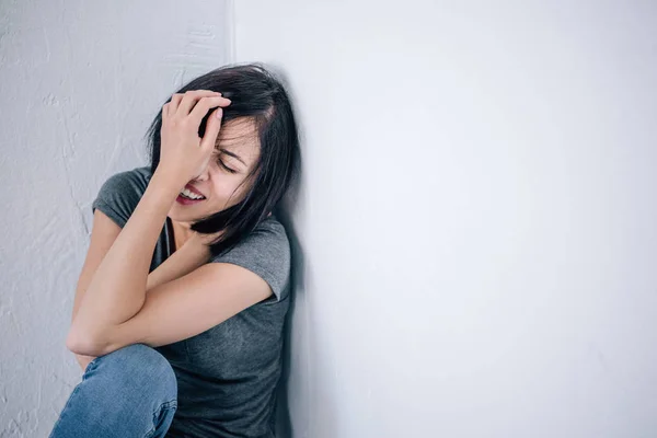 Molesto mujer morena solitaria llorando y cubriendo la cara en casa - foto de stock