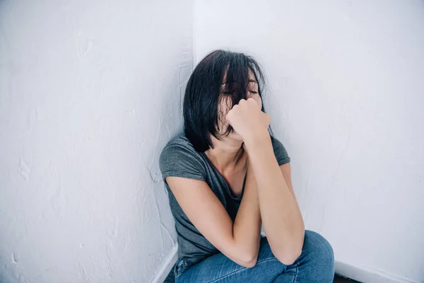 Depressive brünette Frau sitzt und bedeckt Mund zu Hause — Stockfoto