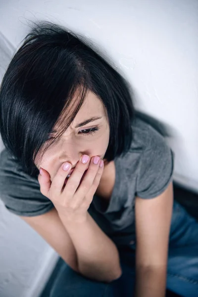 Hochwinkelaufnahme einer depressiven brünetten Frau, die zu Hause den Mund bedeckt — Stockfoto