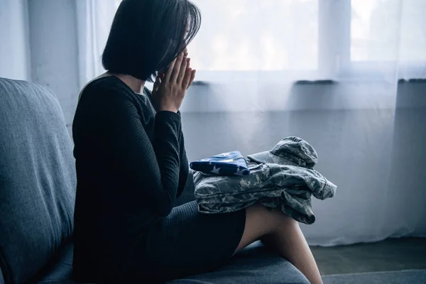 Mulher deprimida no sofá com roupas militares em casa — Fotografia de Stock
