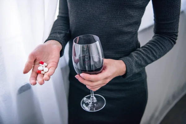 Vista parcial de la mujer deprimida con copa de vino y pastillas en casa - foto de stock