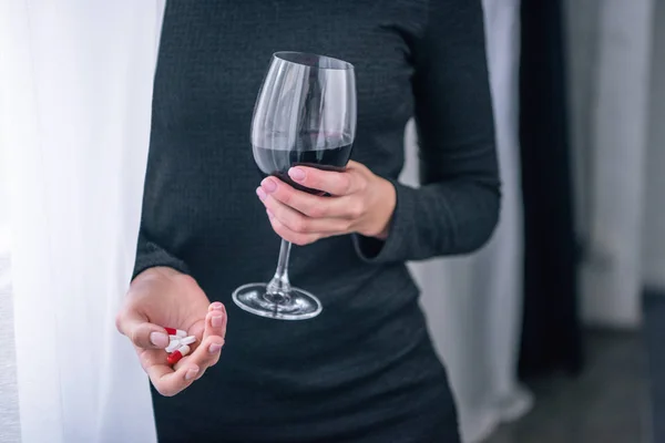 Vue recadrée de la femme déprimée avec verre à vin et pilules à la maison — Photo de stock