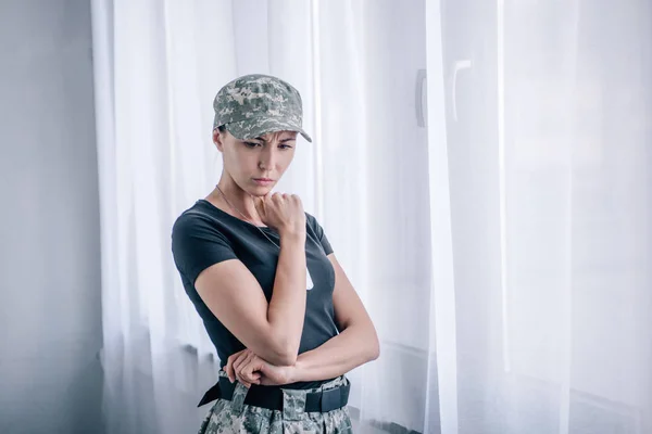 Depressed pensive woman in military uniform touching chin at home — Stock Photo