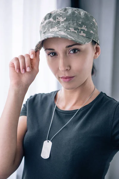 Belle femme en uniforme militaire regardant la caméra à la maison — Photo de stock