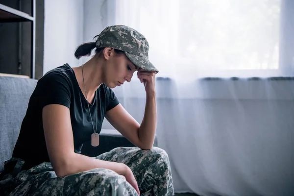 Deprimida mujer solitaria en uniforme militar en casa - foto de stock