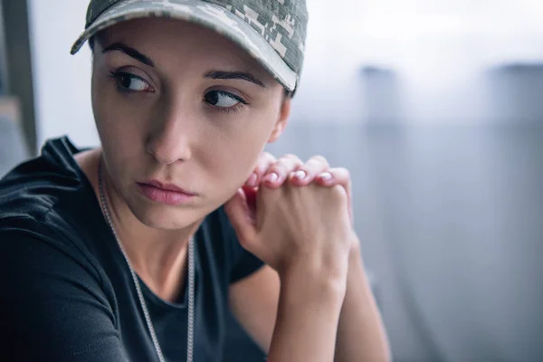 Depressed woman in military uniform and cap at home with copy space — Stock Photo